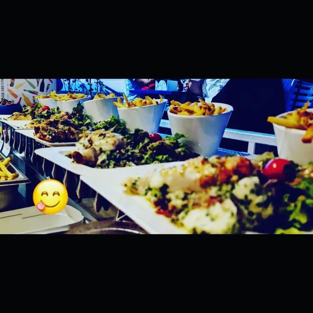 Plats de poisson grillé, salades fraîches et cornets de frites sur une table de restaurant conviviale. 😋