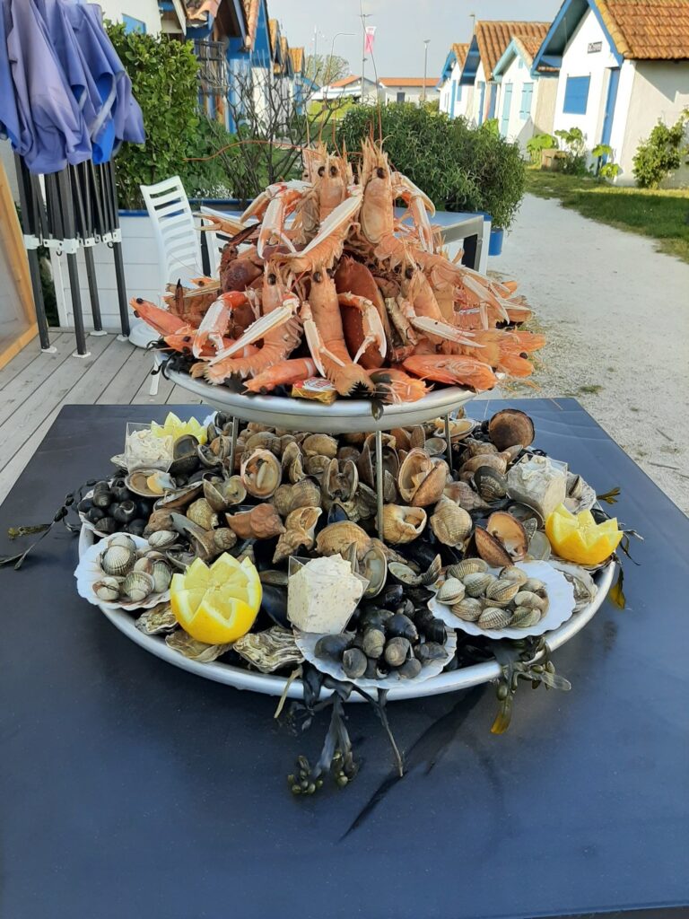 Grand plateau de fruits de mer garni de langoustines, coquillages, huîtres et citrons servis en extérieur.