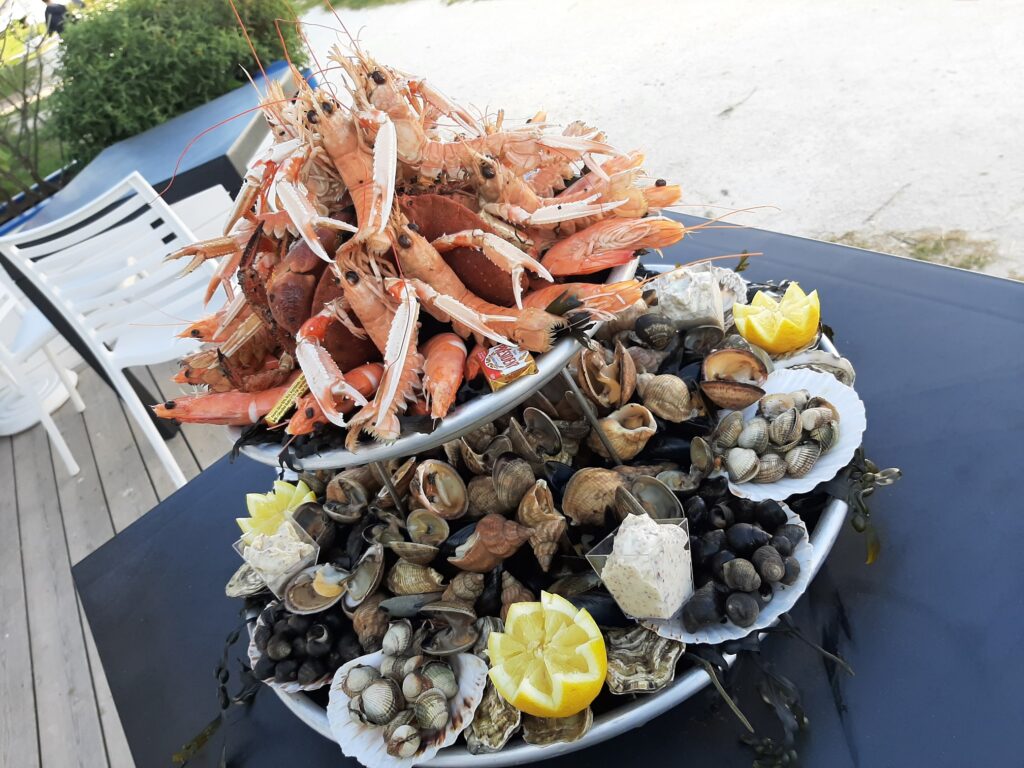 Plateau de fruits de mer à deux étages avec langoustines, crabes et coquillages frais servis en terrasse.